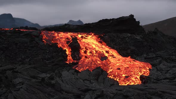 Stunning Icelandic landscape with volcanoes and lava flowing through black rocks alt