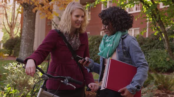 Two college students on campus looking at cell phone