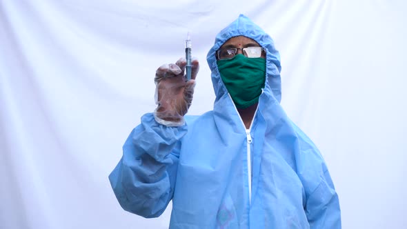 Doctor in PPE kit blue protective suit, surgical mask latex gloves. doctor holding syringe alt