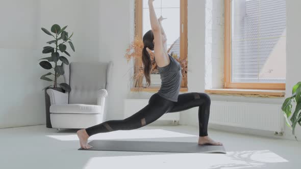 Young Sporty Brunette Girl in Sportswear Does Exercises in Bright Room at Home