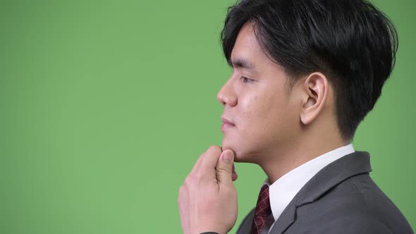 Young Handsome Asian Businessman Against Green Background alt