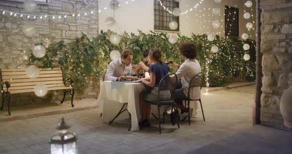 Four People, Two Couples Happy Talking and Eating During a Romantic Gourmet Dinner or Lunch alt