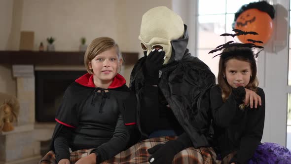 Caucasian Woman Boy and Girl in Halloween Costumes Watching Horror Movie on TV with Scared Facial alt