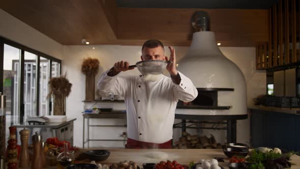 Handsome Chef Sifting Flour Using Sieve in Kitchen alt