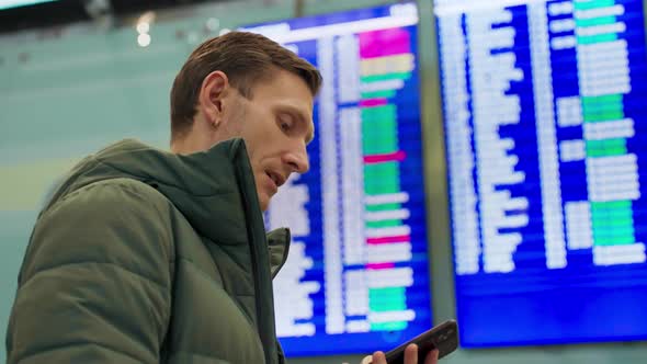 Young Man Looking at Flight Schedule at Airport