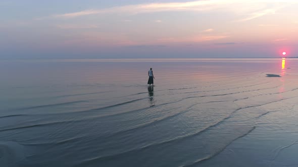 Woman Walking in Sea Water at Sunset