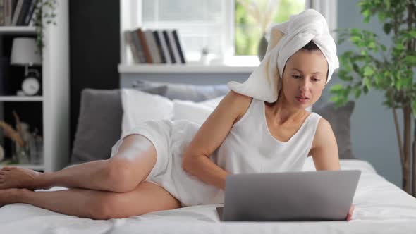 Woman Resting on Bed with Laptop