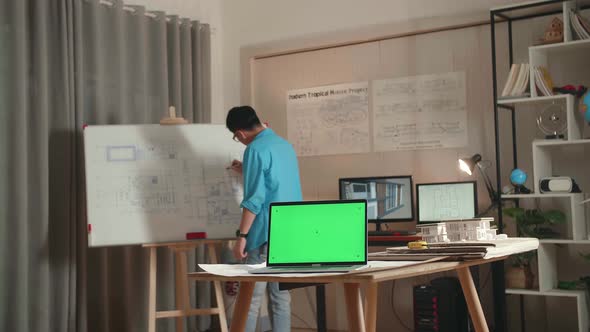 Asian Man Engineer With Green Screen Laptop Drawing Blueprint On The Whiteboard At The Office alt