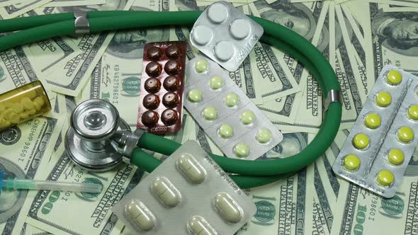 Dollars And Medical Stethoscope With Medicines On The Table alt