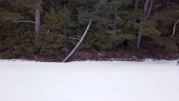 Get an aerial view of Ice Fishing on Fitzgerald Pond, Maine. Fly across the tree line to reveal camp alt