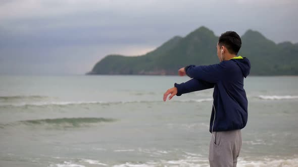 Handsome man running on the beach, Sportsman stretching before running along the beach.