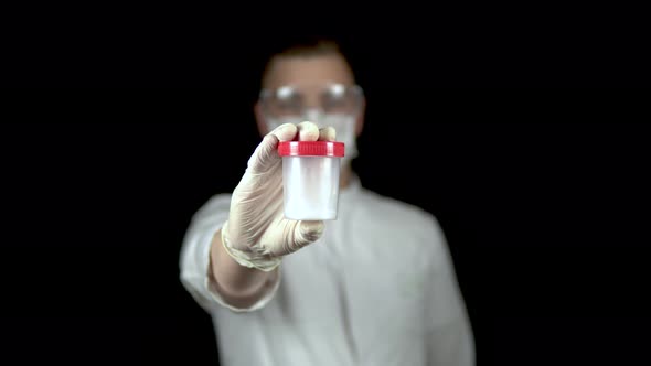 Sperm in a Test Bank Close-up. Man Doctor Holds Out a Jar of Sperm To the Camera on a Black alt