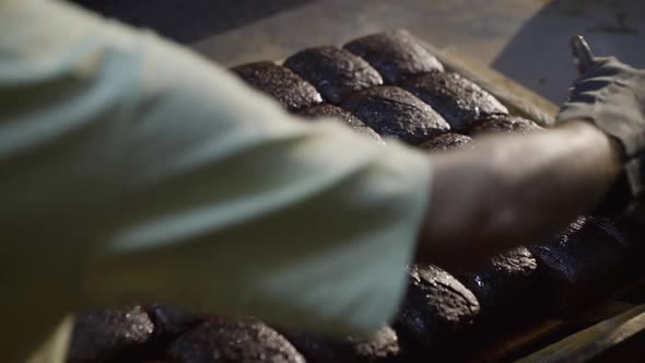Process of Greasing Loaves of Rye Bread and Sprinkling Them with Seeds at Bakery alt