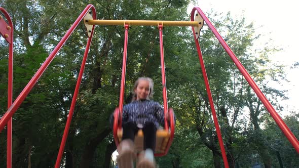 Close Up View on Happy and Smiling Teen Girl Riding a Swing