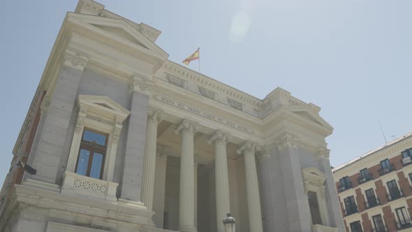 Landmark building architecture with waving Spain flag on top in Madrid, orbit motion alt