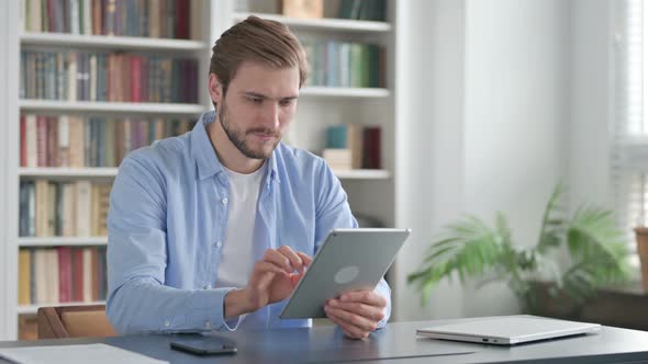 Man Celebrating Success on Tablet in Office alt