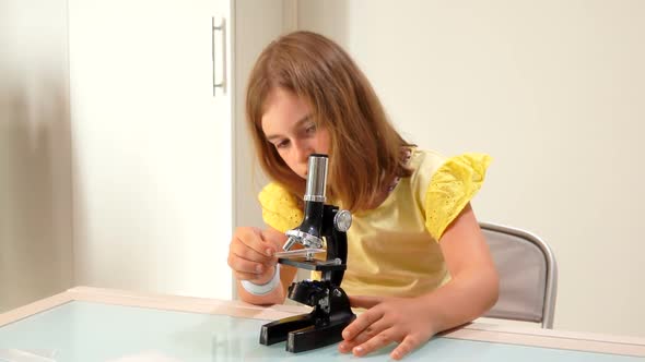 Girl Inserts a Glass Slide Into the Microscope alt