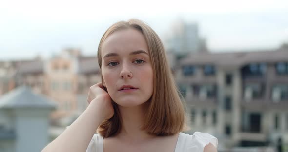 Portrait of the Young European Woman with Nose Earring in White Dress in the City She Smiles alt