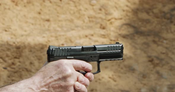 Slow motion of a man firing a hand gun in a firing range with cartridge flying away