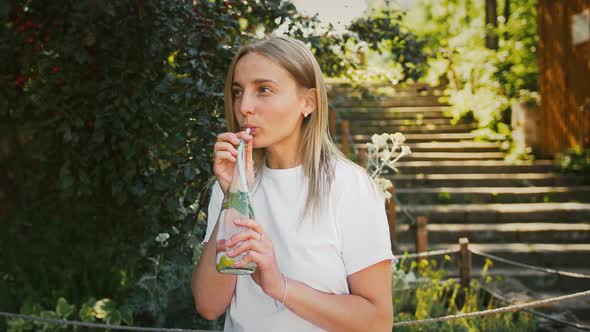 Young Lady is Sitting on a Bench of City Park alt