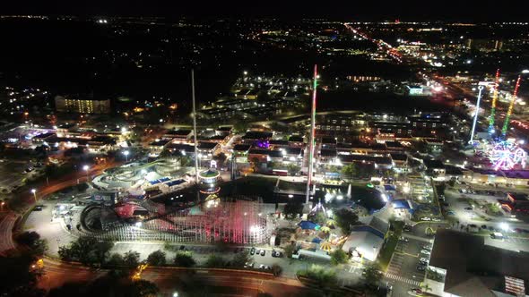 Glowing fun park at night time in Orlando. Aerial orbit view. Ferris wheel and many rides alt