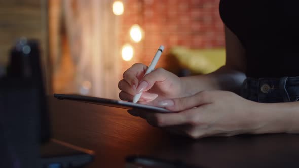 Woman Artist Draws on Graphic Tablet While Sitting at Table Using Stylus Side View Closeup alt