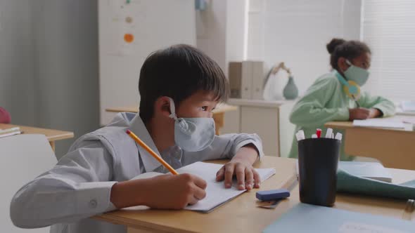 Asian Schoolboy in Face Mask in Classroom alt