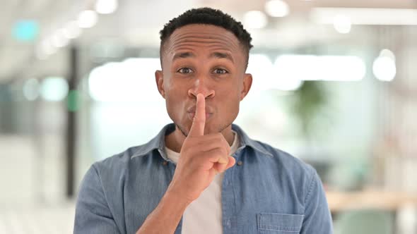 Portrait of Casual African Man Putting Finger on Lips, Quiet Sign  alt