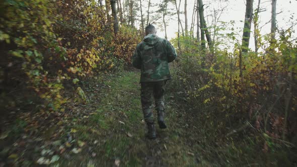 Soldier Jogging and Looking for a Trace of the Enemy with a Rifle in a Forest alt