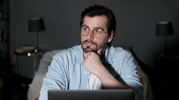 Close up of concentrated young man in headphones with laptop computer working at home alt