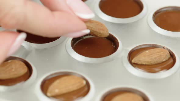 Close-up Making Hand-crafted Chocolate Candies, Adding Almond Nuts To Praline