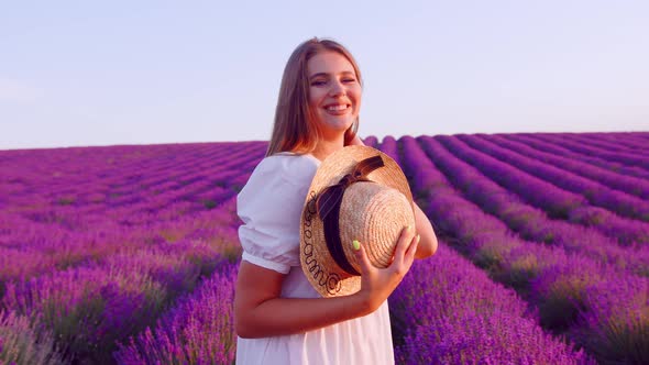 Beautiful Young Woman Wearing White Dress and Hat Standing in a Lavender Field