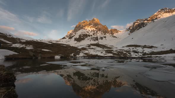 Time-lapse of Sunset in Snowy Mountains. There Is a Lake with Ice Floes