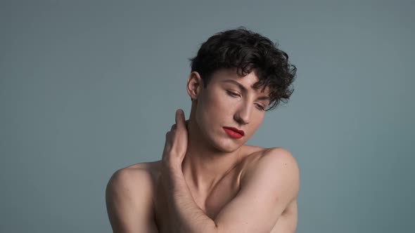 Androgyny. Transgender guy with makeup posing on grey background alt