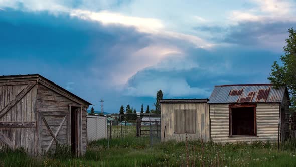 Storm clouds building in the sky over old farm sheds alt
