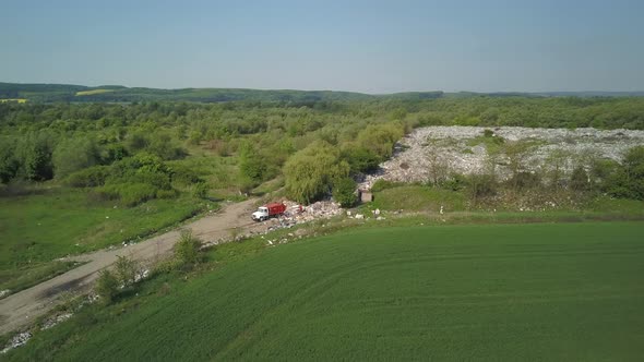 A Garbage Truck Arrives at a Natural Landfill. People Dump Waste at the Entrance. Aerial Video.