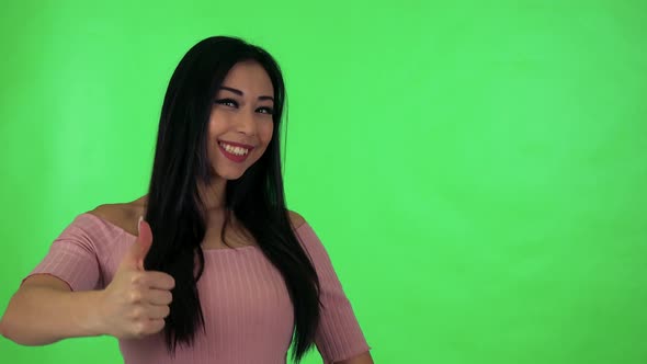 Young Attractive Asian Woman Shows Thumb on Agreement - Green Screen Studio alt