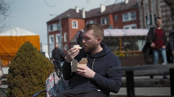 Bearded Young Man Eating Food on the Street