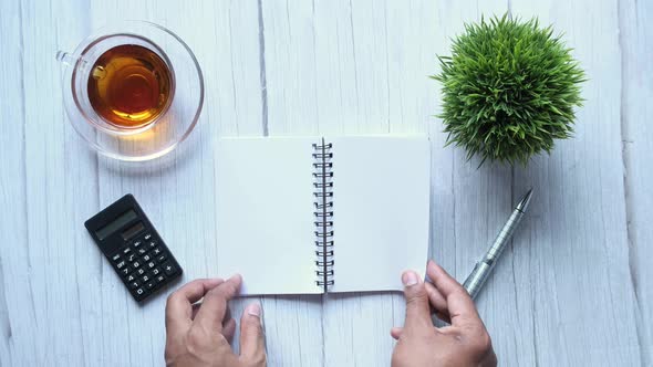Top View of Man Hand Turning Pages of Notepad  alt