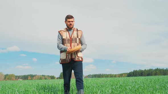 A Young Peasant Man Is Sowing the Field with Grain at a Village alt