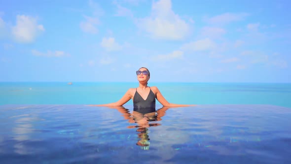 Young asian woman enjoy around outdoor swimming pool for leisure alt