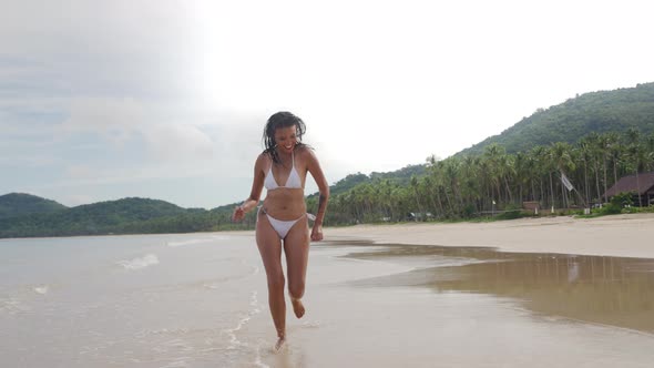Young Woman In Bikini Running Along Beach alt