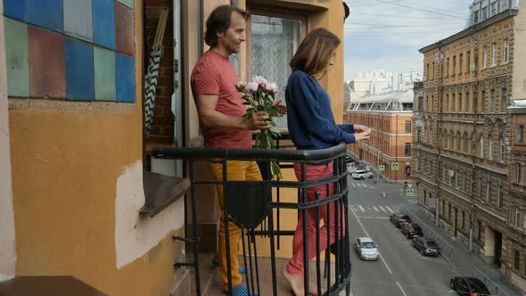Man Gives His Lady a Bunch of Peonies Flowers on Balcony in Downtown