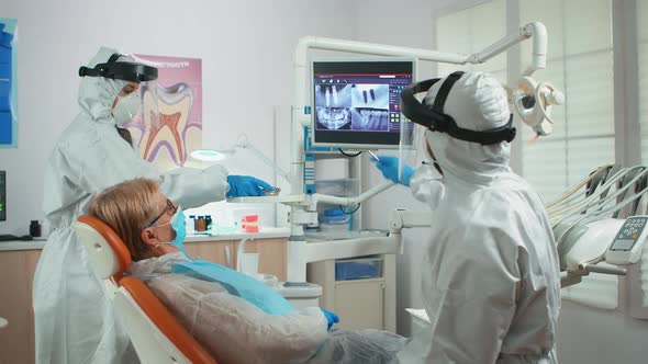 Orthodontist in Special Equipment Pointing on Digital Xray alt