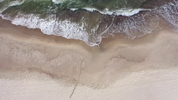 AERIAL: Top View of Couple Walking on a Cloudy Day on Beach with Bare Foots alt