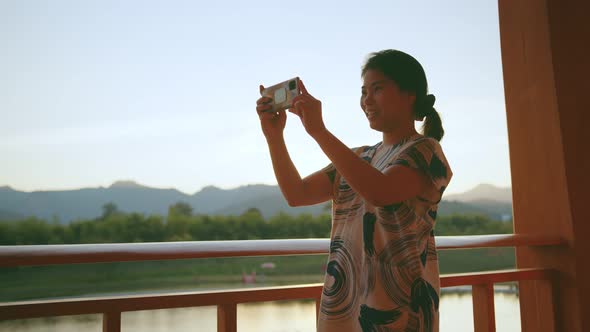 young asian female traveller enjoy walking and sight seeing hand use smartphone taking photo