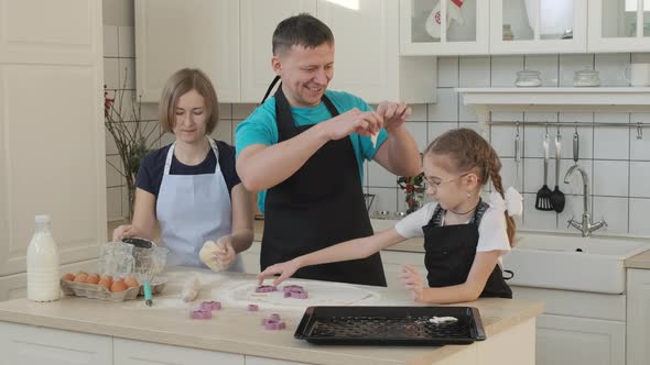 Family of Three Cutting Cookies of Dough at Home alt