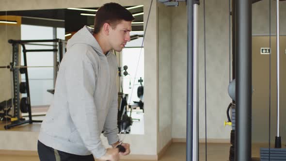 Young Man in Gray Hoodie Training Arms in a Gym