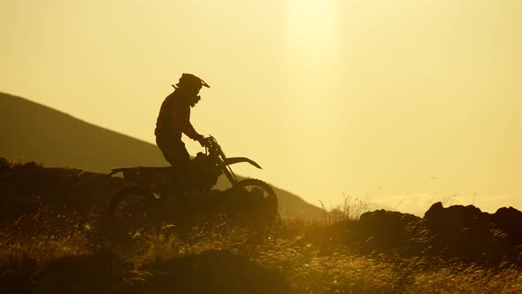 Silhouette of Extreme Pro Motocross Biker Riding Motor Bike Opposite Sunset
