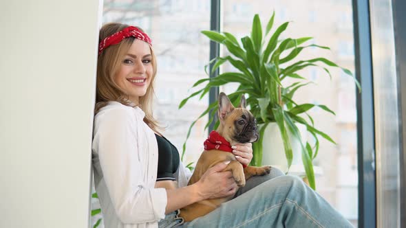 Beautiful Woman with a French Bulldog Dog in Her Arms Sitting and Looking Directly in Camera alt